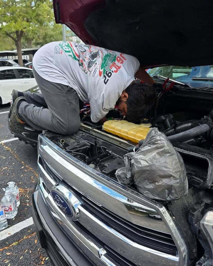 Bears Mobile Mechanic kneeling on a truck, working in the engine bay in a parking lot in Orlando, FL