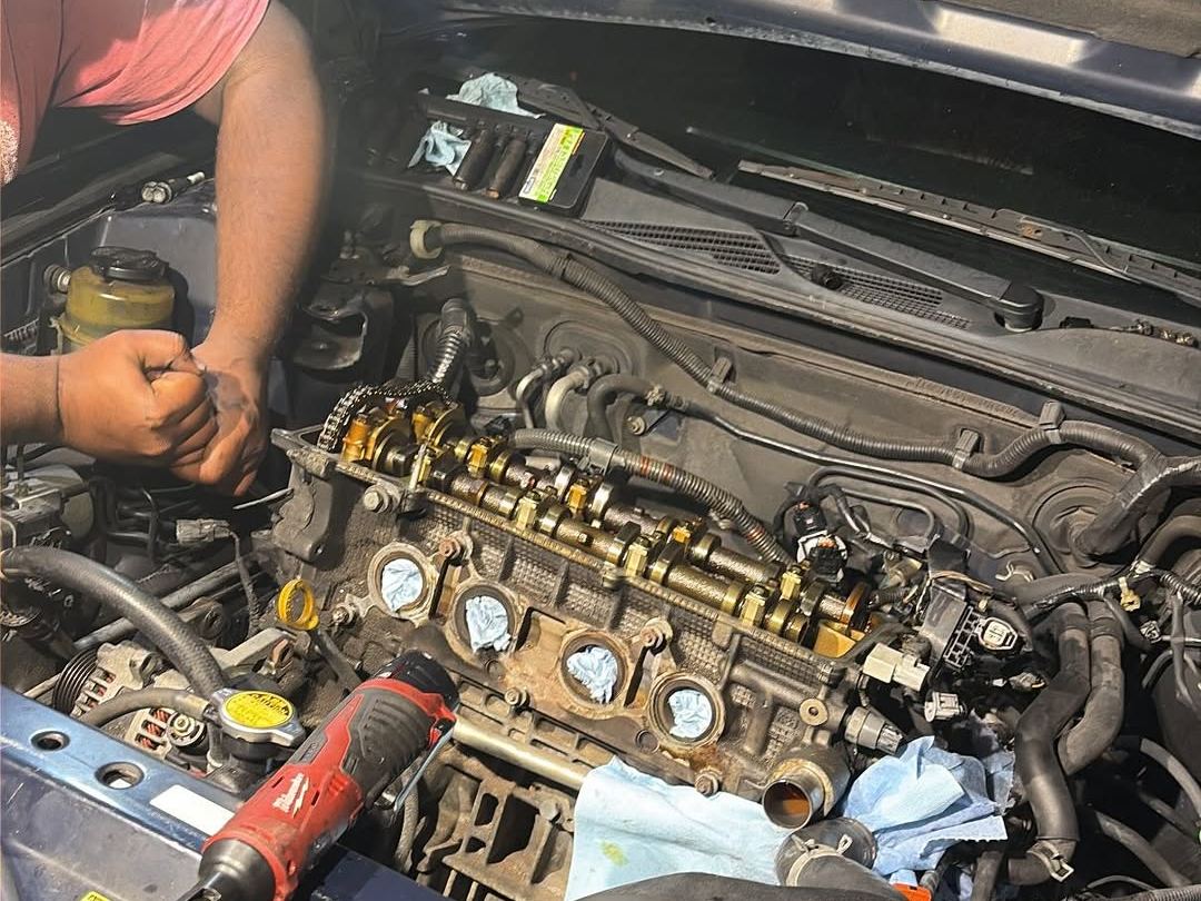 Hands working on an exposed valvetrain with the coils and plugs out