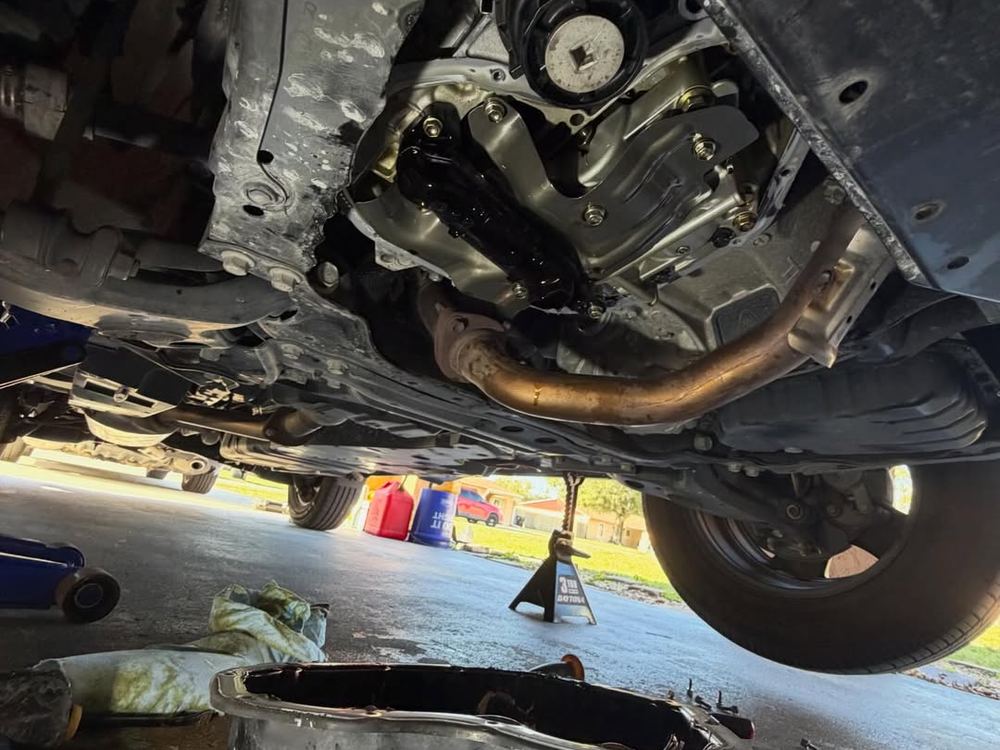 Vehicle raised on jack stands with the underside exposed for fluid service